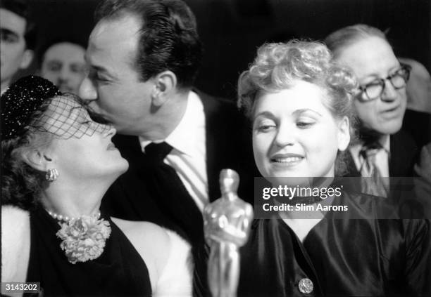 American actor Jose Ferrer commiserates with Gloria Swanson after she lost out in the contest for the Best Actress Oscar, while the winner, Judy...