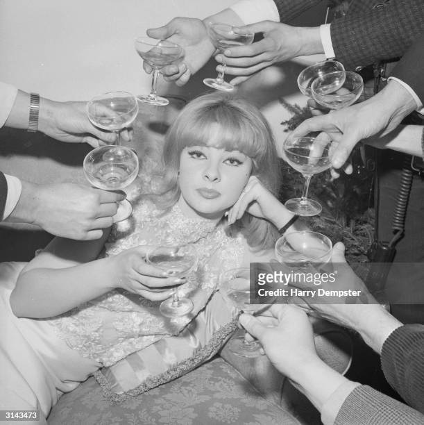 Mandy Rice-Davies, a Welsh showgirl and witness in the Profumo affair, surrounded by champagne at the press launch of her book 'The Mandy Report'.