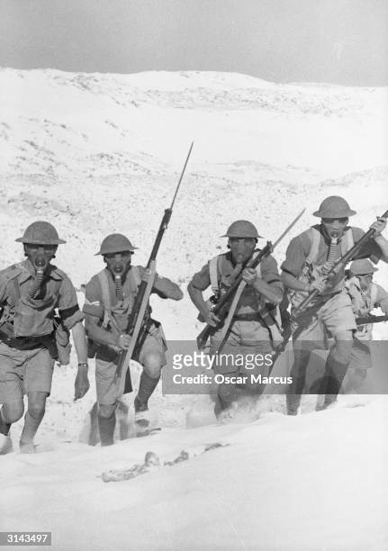 British infantry advancing, wearing gas masks, during exercises at Mersa Matruh in Egypt.
