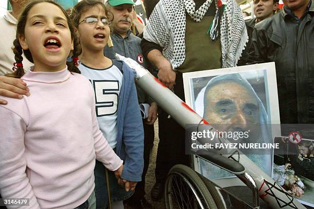 Palestinian girls shout anti-Israel and anti-USA slogans next to assassinated Hamas spiritual leader Sheikh Ahmed Yassin's portrait in a wheelchair...