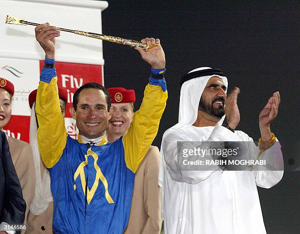 Jockey Alex Solis holds up the trophy after his victory at the Dubai World Cup 27 March 2004 as Dubai Crown Prince and UAE Defense Minister Sheikh...