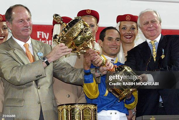 Trainer Richar Mandella raises the Dubai World Cup trophy with US jockey Alex Solis and Gerald Ford, the American owner of Pleasantly Ferfect, 27...