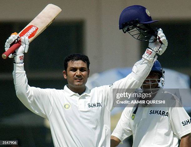 Indian batsman Virender Sehwag celebrates his century as his teammate Akash Chopra looks on during the first day of the first Test match between...