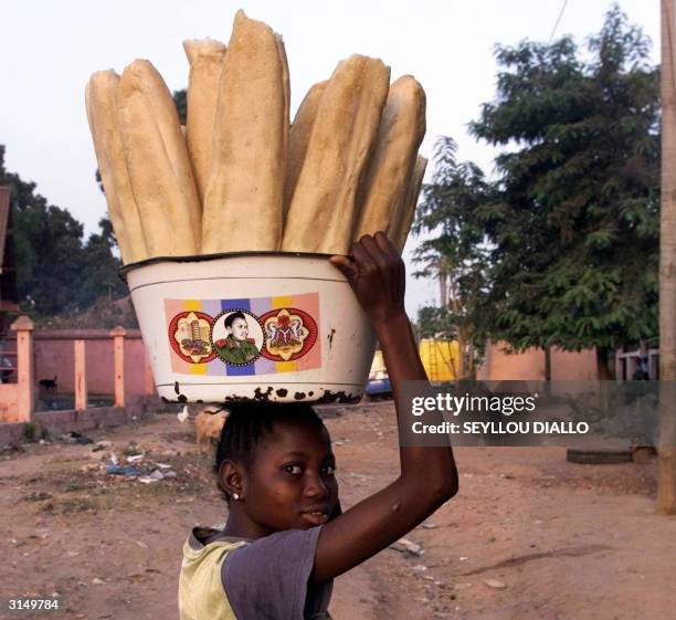 Young bread seller carries her merchandise in a suburb of Bissau 28 March 2004, the day of the legislative elections in Guinea Bissau. The elections...