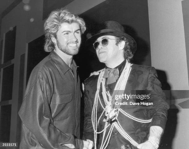 Pop star Elton John congratulates George Michael on winning the Ivor Novello Songwriter of the Year Award at London's Grosvenor House Hotel, 13th...