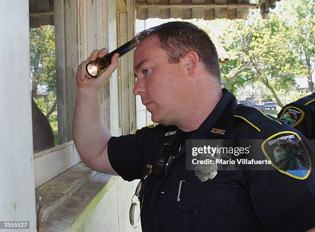 Shreveport Police Officer E.J. Swartout looks through the window of a suspected drug house March 29, 2004 in Shreveport, Louisiana. The 5th Circuit...