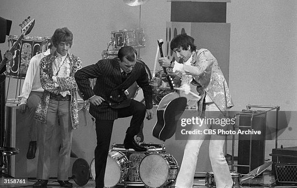 Guitarist Pete Townshend helps host Tom Smothers destroy his acoustic guitar as singer Roger Daltrey looks on, following British rock group The Who's...