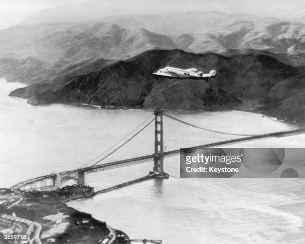 The Lockheed Electra 'Flying Laboratory', piloted by American aviator Amelia Earhart and Fred Noonan flies over the Golden Gate bridge in Oakland,...