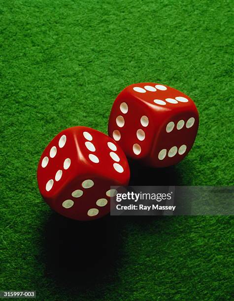 two red and white dice on green felt,close-up - dice pair stock-fotos und bilder