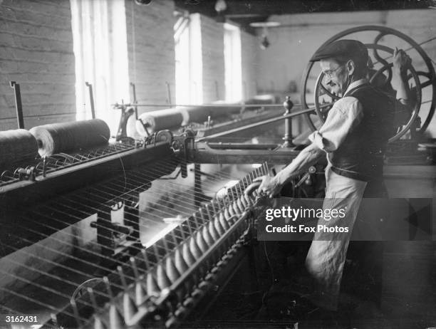 Worker threading yarn at Priory wool factory in Brecon.