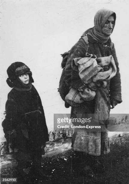 Carrying everything she owns under her arm, a Russian woman and her small son search for food during the famine.