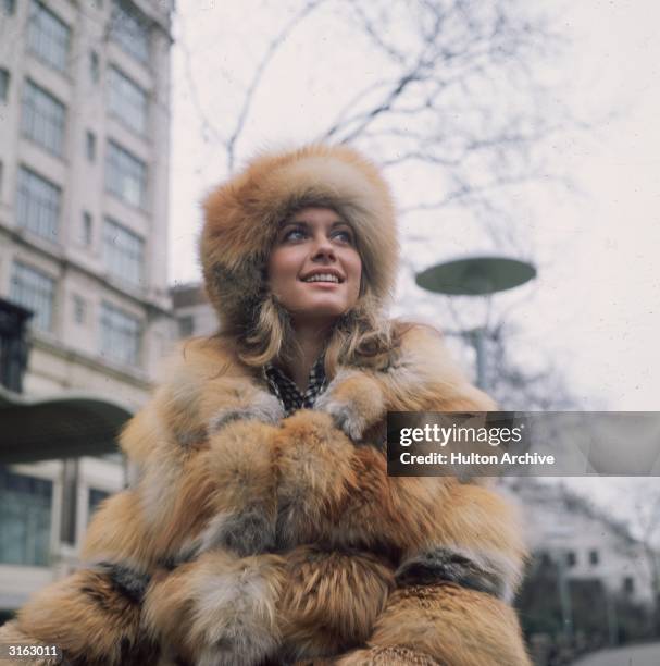 Australian actress Olivia Newton-John wearing a heavy fur coat outside the Savoy Hotel in London.