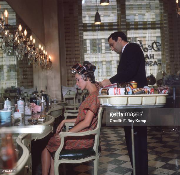 Hairdresser styling a woman's hair using beer cans as curlers .