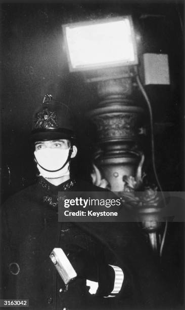 Reg Nicol, a policeman in the City of London, wearing a mask as protection against a severe smog which has virtually blacked out the capital....