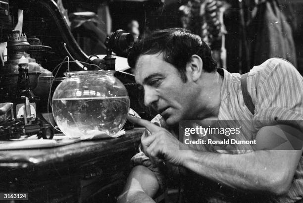 Harry H Corbett , star of the 70s television show 'Steptoe and Son', peers into a goldfish bowl on set.