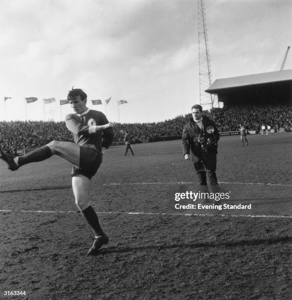 Liverpool football player Tommy Smith in action followed by a photographer.