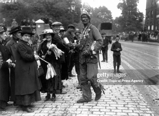 Man in fancy dress collects money from the by-standers during a peace carnival in Camberwell, London.