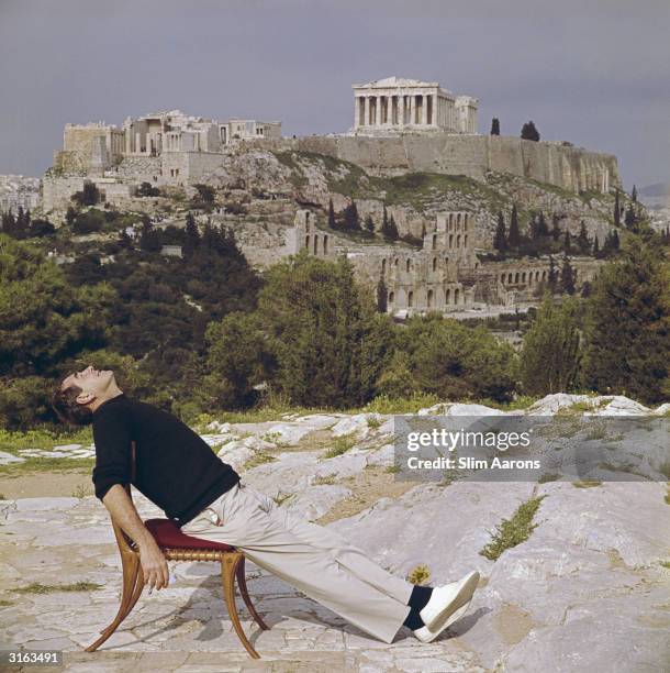 Photographer Slim Aarons slouches in a chair with the Acropolis and its surroundings as a backdrop.