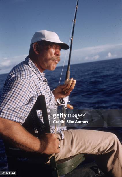 Actor Ward Bond has a sandwich on a fishing trip during a break from filming in Mister Roberts. He plays the part of Chief Petty Officer Dawdy.