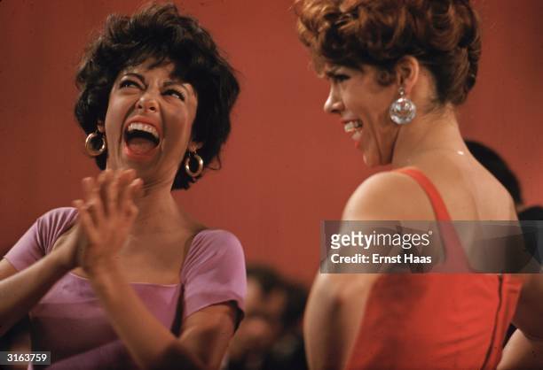 Rita Moreno shares a joke with a co-star on the set of the musical 'West Side Story', directed by Robert Wise and Jerome Robbins.