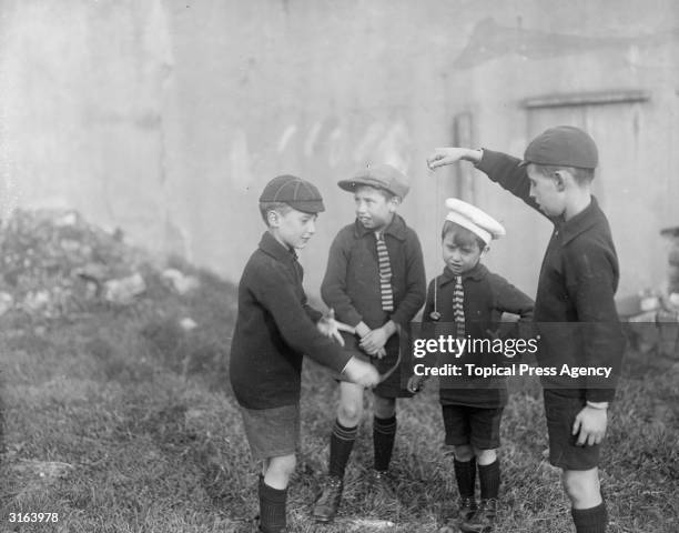 Boys playing a game of conkers with horse chestnuts on strings.