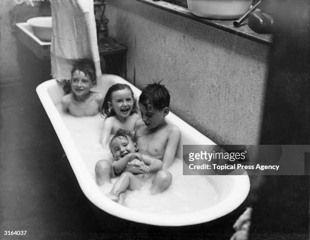 Children cooling off in a bathtub of water during a heatwave.