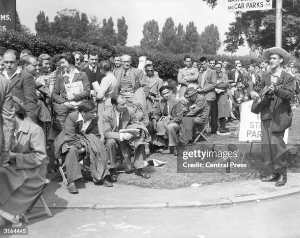 Busker entertains queues waiting to see the Men's Singles Final between Australia's Frank Sedgman and Budge Patty of the United States at Wimbledon.