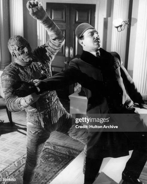 Christopher Lee in the role of Kharis the mummy, attacking George Pastell, playing Mehemet, in a scene from the film, 'The Mummy', directed by...