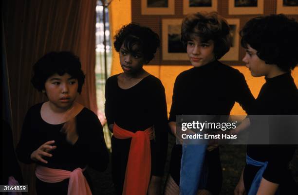 Young girls in black leotards worn with coloured sashes.