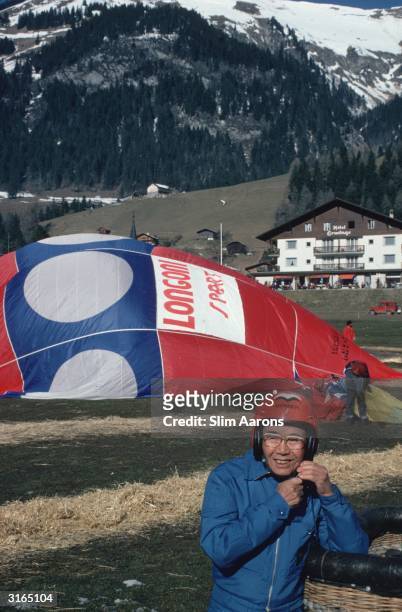 Soichiro Honda , founder of the Honda motor company, fastening his helmet while waiting for his hot air balloon to inflate in Gstaad, Switzerland.