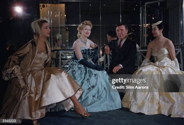 Couturier and court dressmaker Norman Hartnell with three models at his Burton Street salon, London.