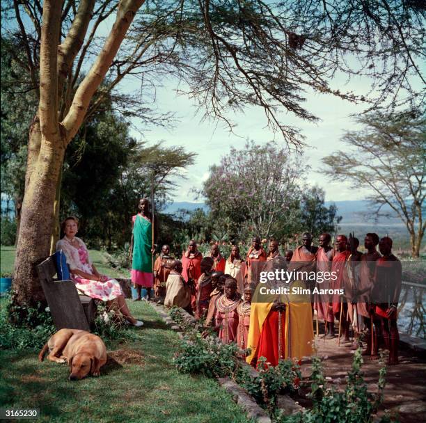 Lady Hamilton rests in the shade of a tree, in the company of a Kenyan tribe.
