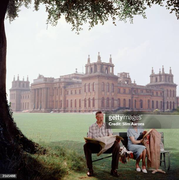 John Albert Edward Spencer Churchill, the 10th Duke of Marlborough and his wife Mary relax on a bench in the grounds of Blenheim Palace, the family...