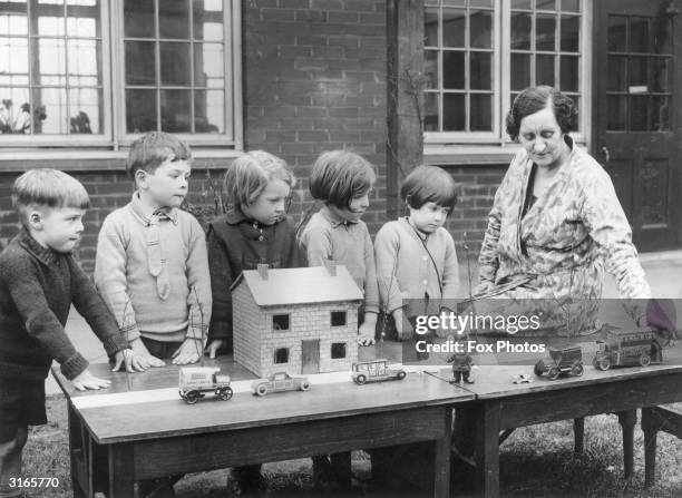 Safety First' lesson in progress at Layton Junior School, Blackpool, Lancashire. A group of youngsters watch a teacher move toy cars on a model...