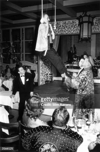 Film producer and screenwriter Darryl F Zanuck takes to the trapeze at his daughter's fancy dress party in Ciros, Hollywood. Actor Clifton Webb lends...