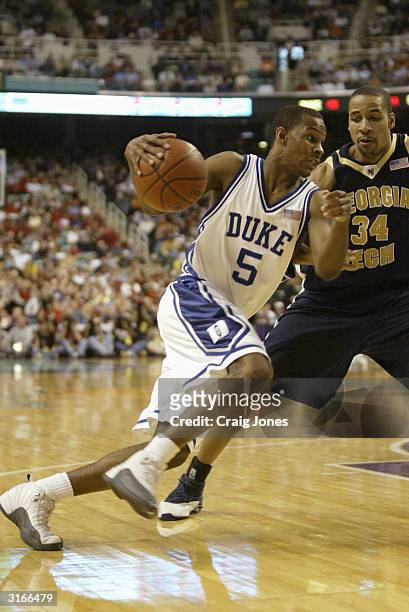 Daniel Ewing of the Duke Blue Devils drives on Robert Brooks of the Georgia Tech Yellow Jackets during their ACC Semifinal game on March 13, 2004 at...