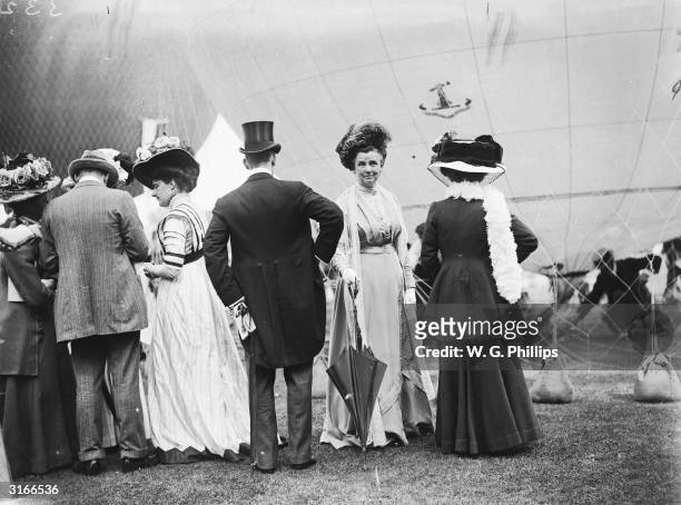 Edwardian ladies and gentlemen attend a hot air ballooning event.