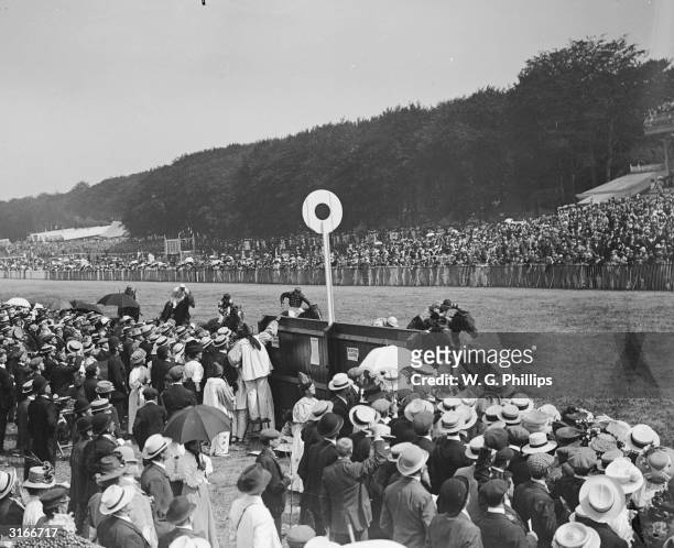 Spectators cheer on the riders and horses during a horse race at Goodwood.