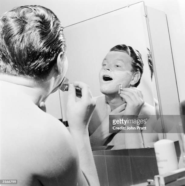 English comic Benny Hill thinks up a few gags during his morning shave at his new flat in London's Maida Vale.
