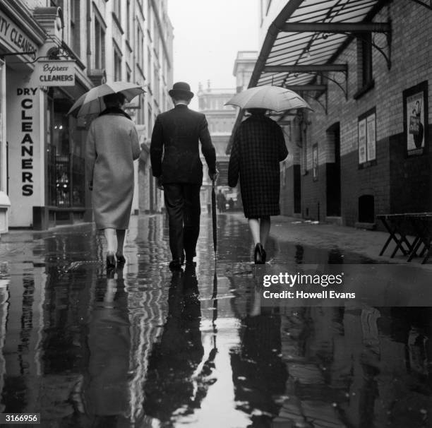 This city gent has forgotten what his umbrella is for as the rain falls on the streets of London.