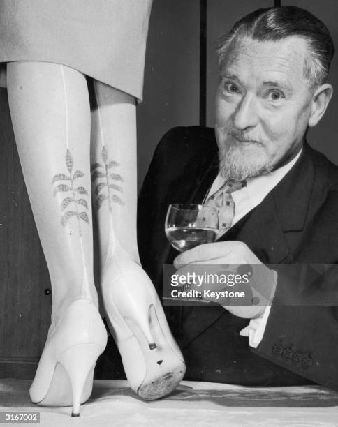 Man examines a prototype of a new range of hand-painted stockings with a leaf motif by the designer Elsa Schiaparelli.