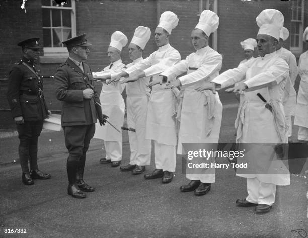 Captain S L Delahay, Chief Instructor at the Army School of Cookery at Buller Barracks, Aldershot, inspects his chefs' hands for cleanliness. These...