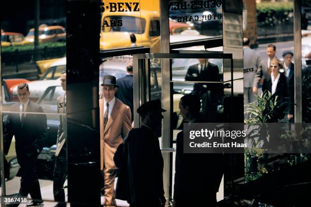 Pedestrians pass the glass window of a Mercedes Benz motor car showroom in New York City.