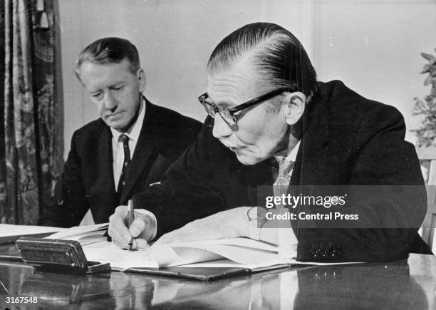 The Rhodesian Premier Ian Smith looks on as Clifford Dupont signs the dissolution of Parliament in Salisbury, Rhodesia. This proclamation came on the...