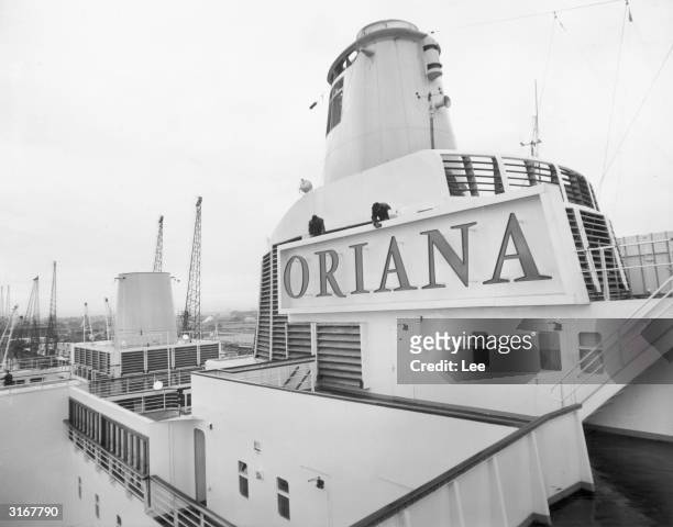 Workmen clean the nameplate of the new P&O liner Oriana, while she docks at Southampton in preparation for her maiden voyage to Australia. The luxury...