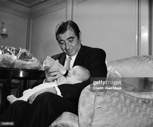 Actor, Robert Newton feeding his baby.