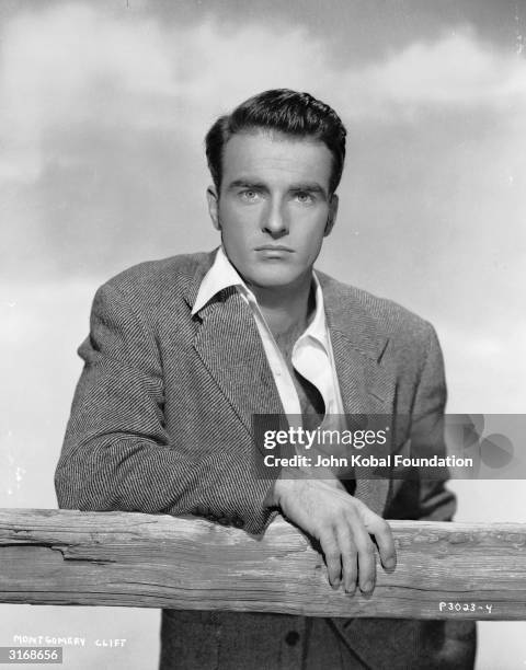 American actor Montgomery Clift leaning on a fence with an intent expression.