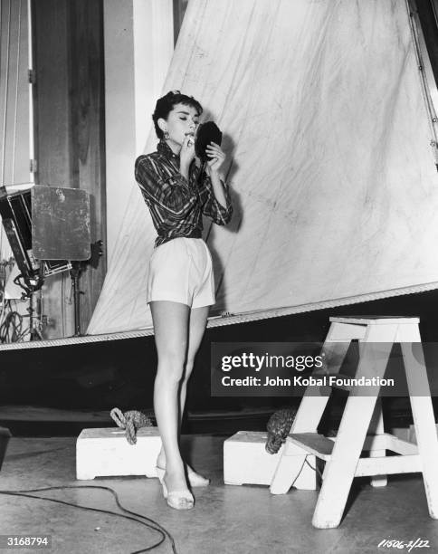 Audrey Hepburn adjusts her make-up off the set of 'Sabrina' , directed by Billy Wilder.