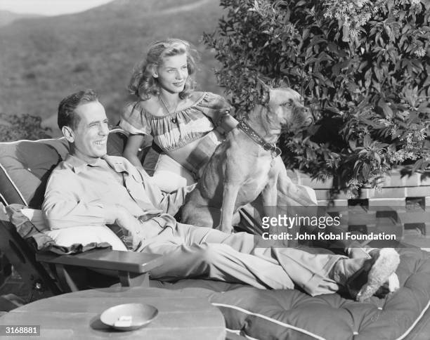 American actor Humphrey Bogart with his wife, Lauren Bacall, and their pet dog.