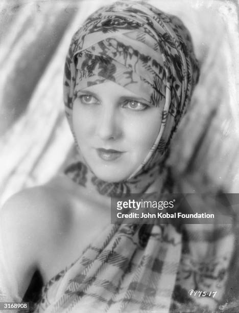 Wearing a headscarf draped like a turban, film star Jean Arthur .